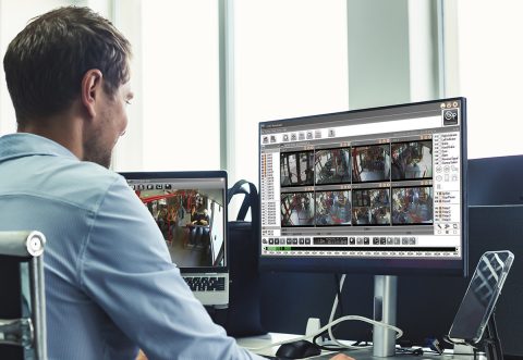 Young man manager businessman broker agent in blue shirt working in corporate office using pc computer at desk, rear view. Concept of business development growth, solutions. Copy ad text space